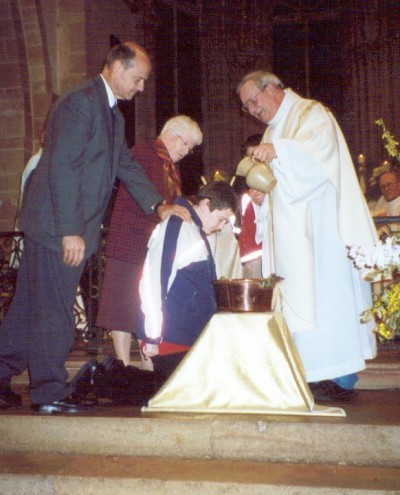 Joshua being baptised while his godfather and godmother lay hands on him
